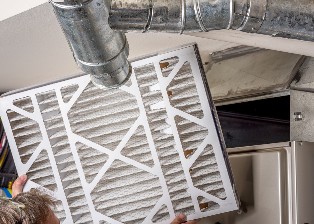 Homeowner inspecting furnace filter in home before winter in Nebraska